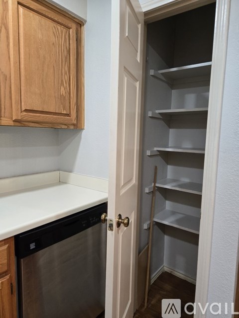 A kitchen with a white counter top and a wooden cabinet.