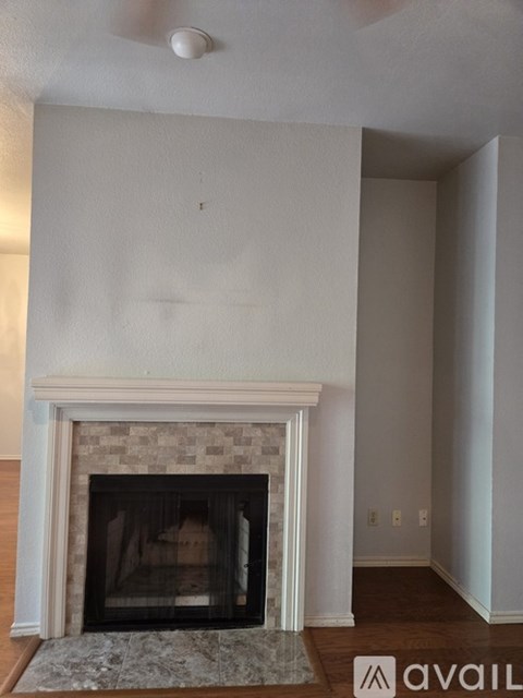 A fireplace with a beige mantle and a rug in front of it.
