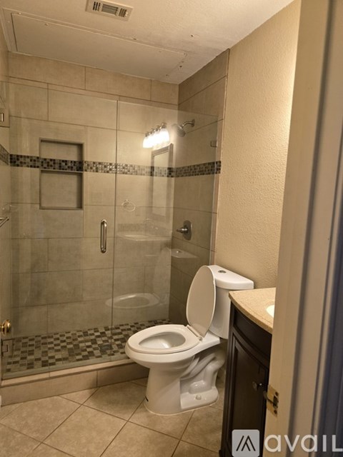 A white toilet in a bathroom with a glass shower stall.