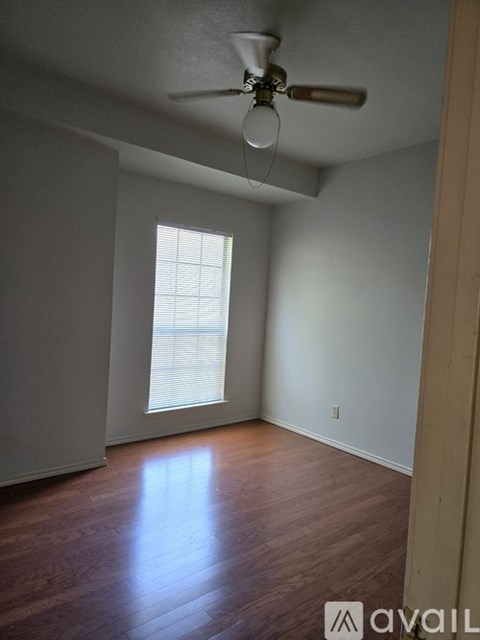 A room with a ceiling fan and a window with blinds.
