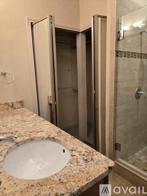 A bathroom with a marble countertop and a walk-in shower.