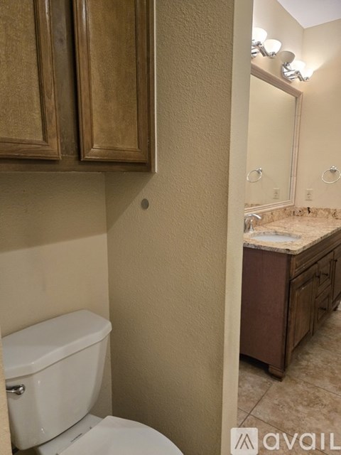 A bathroom with a toilet and a vanity with a mirror.