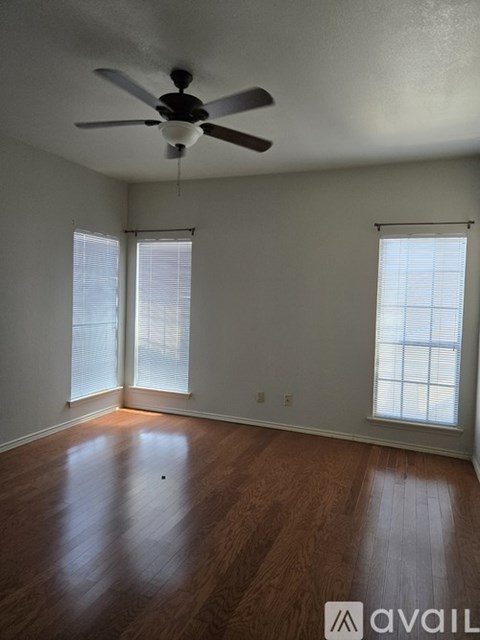 A room with a ceiling fan and wood flooring.