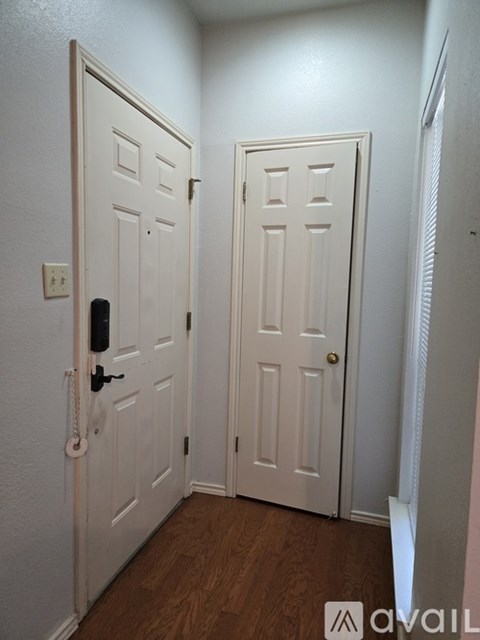 A hallway with two doors and a light switch on the wall.