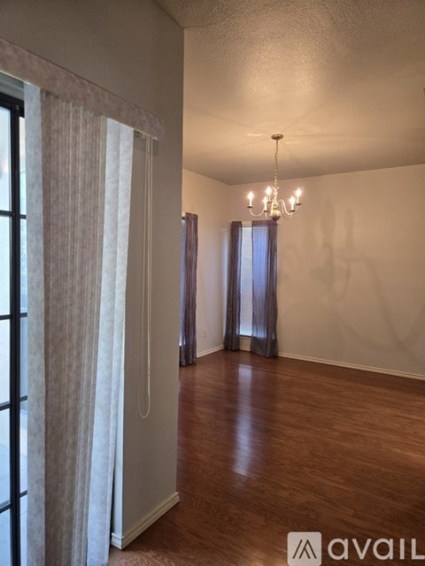 A room with a chandelier and a window with curtains.