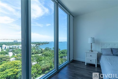 A bedroom with a large window overlooking a cityscape.