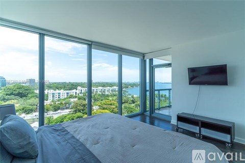 A bedroom with a large bed and a flat screen TV mounted on the wall.