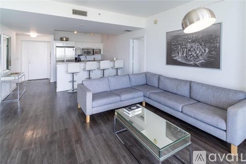 A modern living room with a grey couch and a glass coffee table.