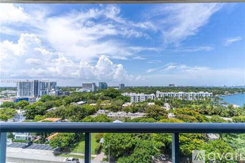 A view from a balcony overlooking a city with buildings and a body of water.