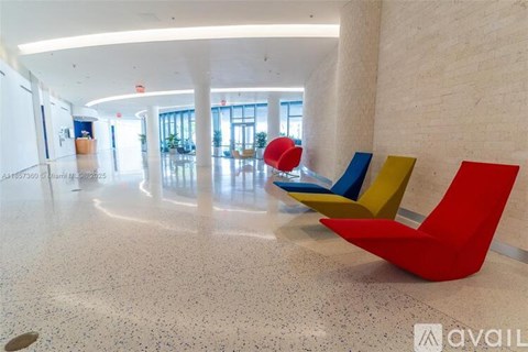 A large room with a white floor and a white wall with a red chair and a blue chair.