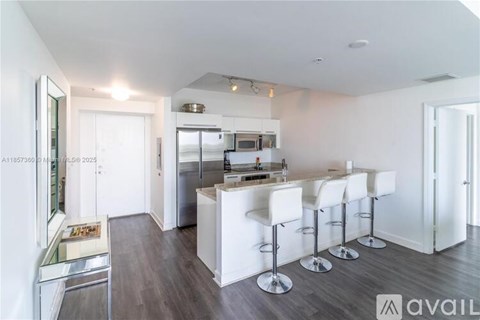 A kitchen with white bar stools and a white fridge.
