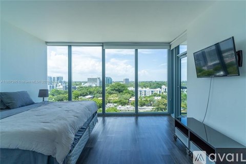A bedroom with a large bed and a flat screen TV mounted on the wall.