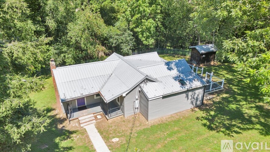 A house with a grey roof is surrounded by greenery.