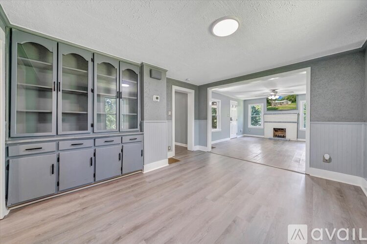 A spacious kitchen with grey cabinets and a wooden floor.