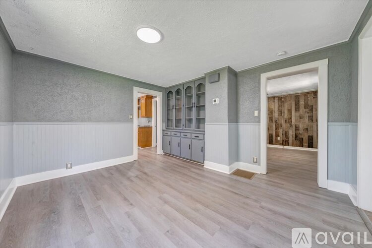 A spacious room with grey walls and wooden flooring.