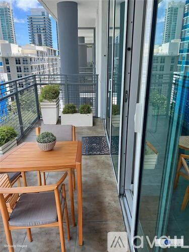 A balcony with a table and chairs overlooking a cityscape.