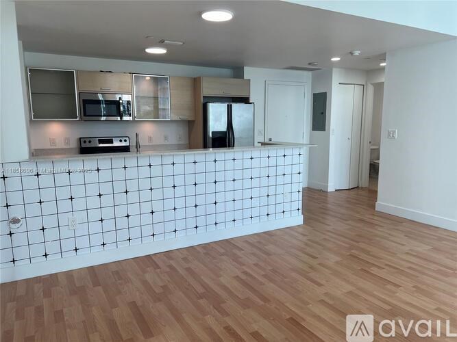A kitchen with wooden floors and a white tiled wall.