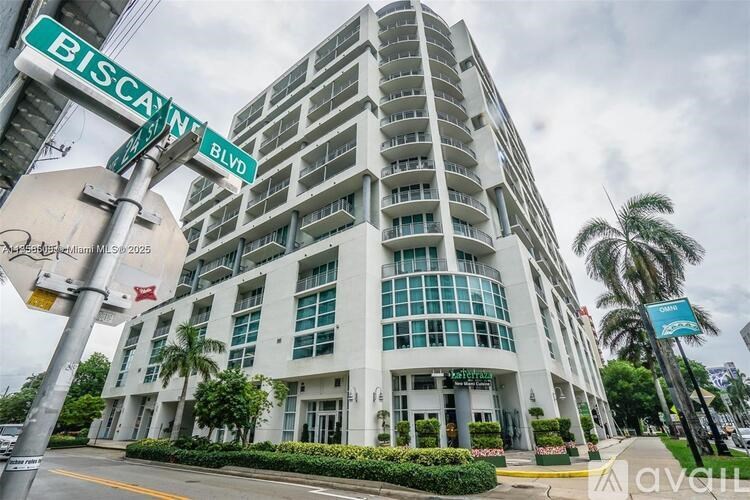 A tall white building with a glass facade is located at the corner of Biscane and Biscane Blvd.