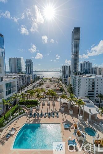 A sunny day at a rooftop pool with palm trees and a city skyline in the background.
