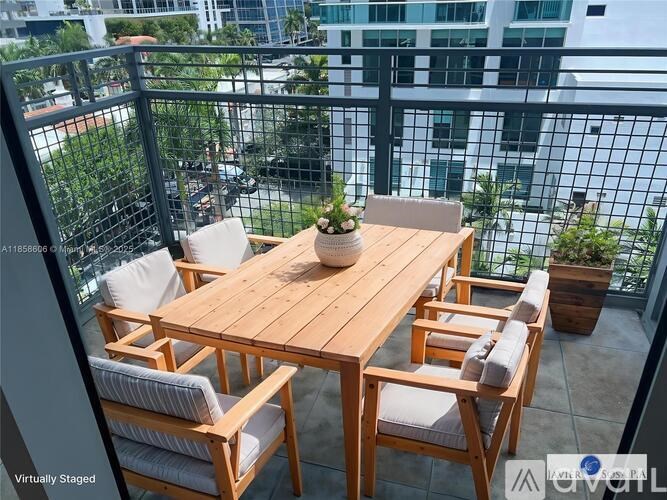 A wooden table with chairs is set up on a balcony with a view of the city.