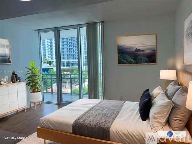 A bedroom with a large bed, a potted plant, and a painting on the wall.