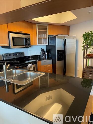 A kitchen with a black counter top and stainless steel appliances.