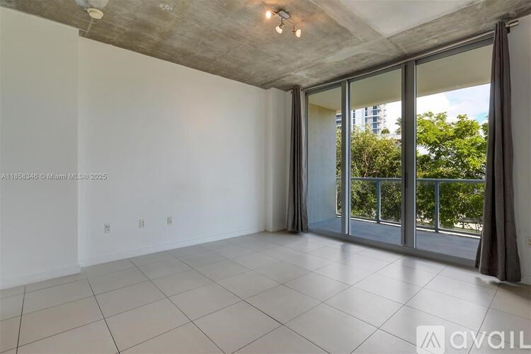 A spacious room with a sliding glass door leading to a balcony.