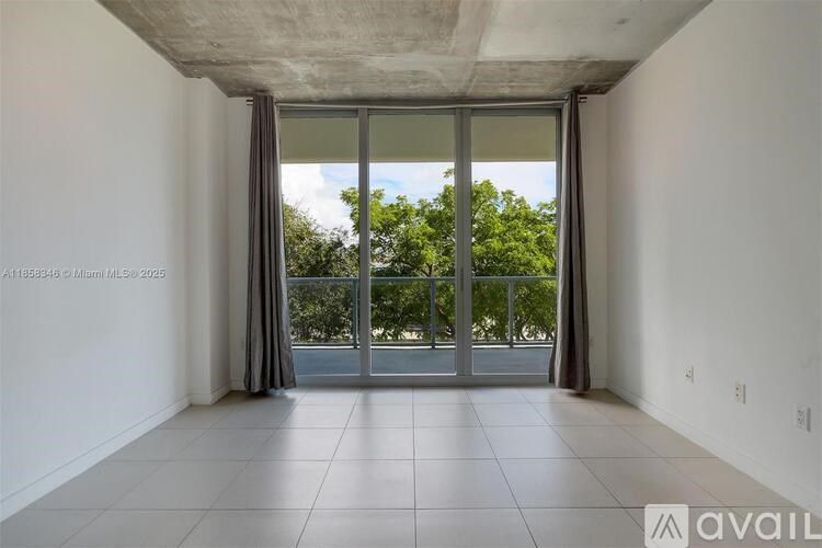 A spacious room with a sliding glass door leading to a balcony.