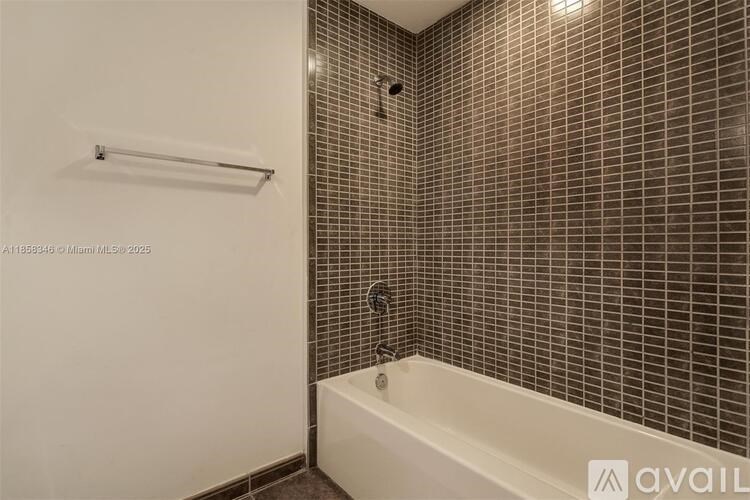 A bathroom with a white tub and brown tiled walls.