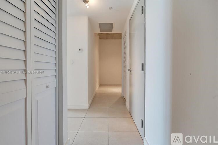 A long, narrow hallway with white walls and a tiled floor.