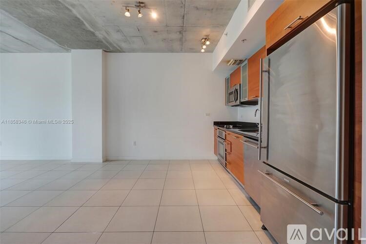 A kitchen with white tiles and a stainless steel refrigerator.