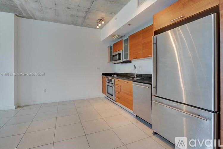 A kitchen with a stainless steel refrigerator and wooden cabinets.