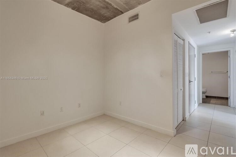 A room with white walls and a tiled floor is available for rent.