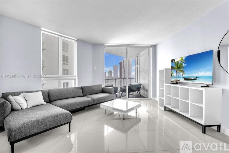 A modern living room with a grey sofa, a white coffee table, and a flat-screen TV.
