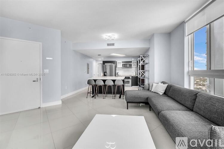 A modern living room with a grey sofa and a dining table with chairs.