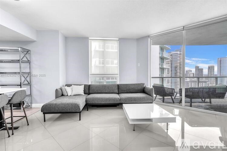A modern living room with a grey sofa and a glass table.