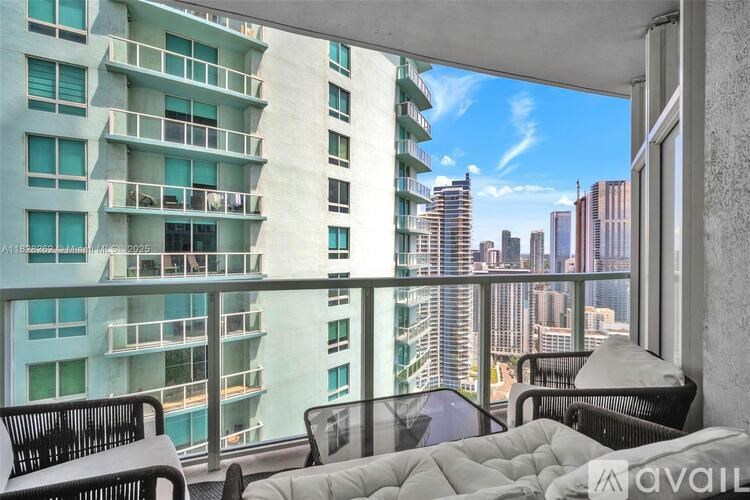 A balcony with a couch and chairs overlooking a cityscape.