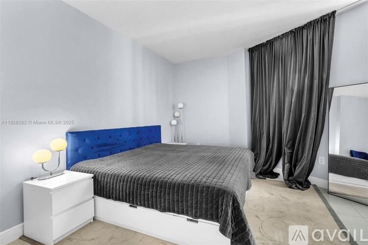 A bedroom with a blue headboard and grey bedspread.