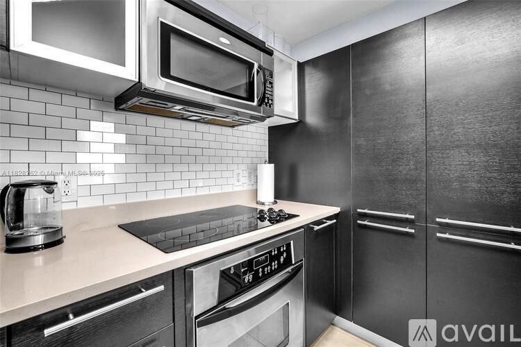 A modern kitchen with black appliances and a white tiled backsplash.