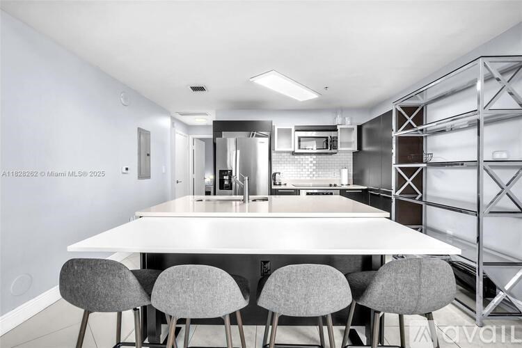 A modern kitchen with a white table and grey chairs.