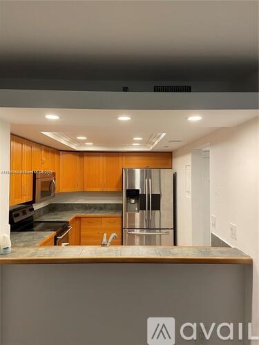 A kitchen with wooden cabinets and a stainless steel refrigerator.