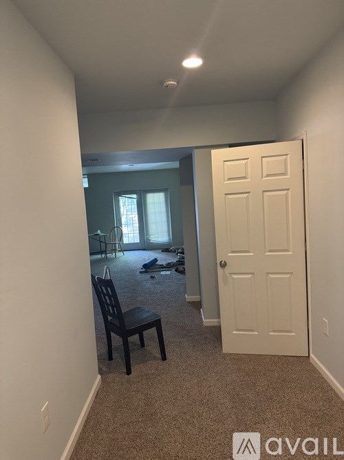 A room with a white door and a black chair.