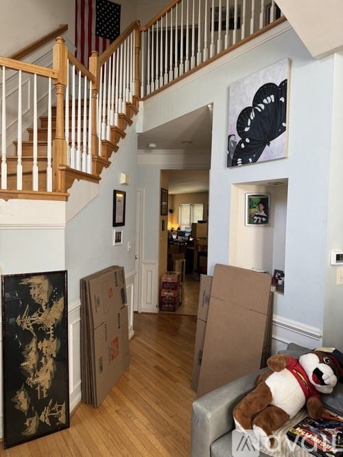 A room with a staircase and a painting leaning against the wall.