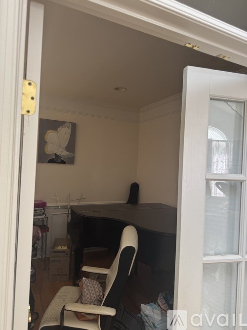 A room with a white chair and a painting on the wall.