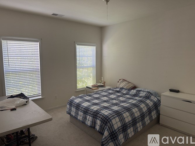 A bedroom with a bed, nightstand, and window with blinds.