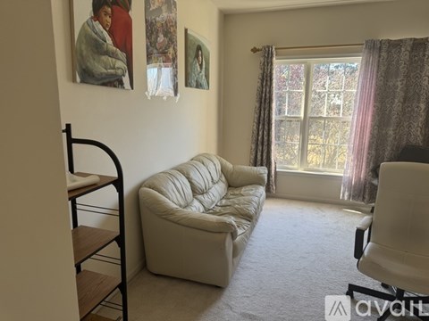 A living room with a white couch and a painting on the wall.