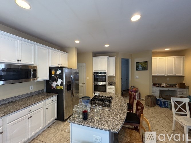 A kitchen with white cabinets and a black fridge.