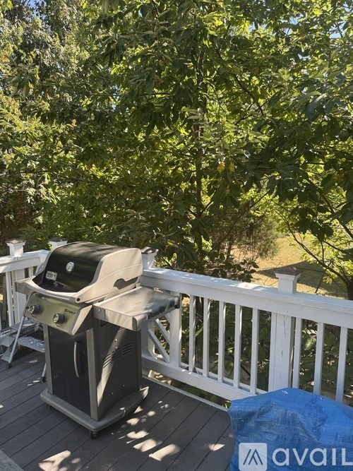 A grill is on a deck with trees in the background.