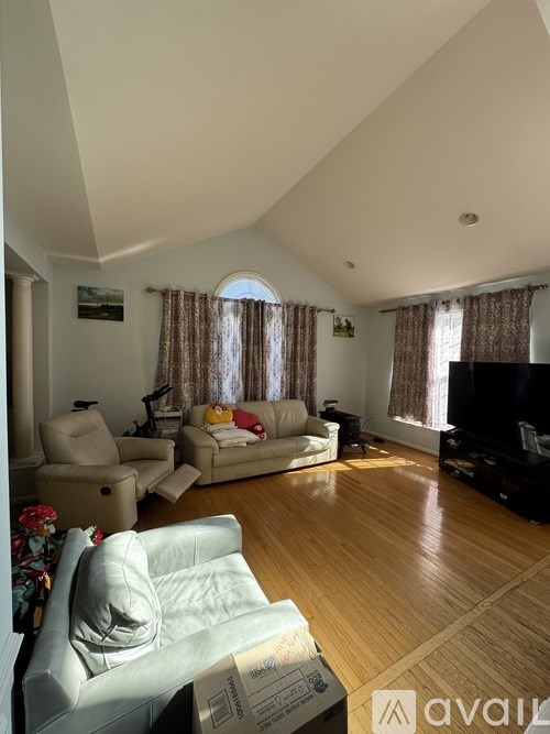 A living room with a sofa, chairs, and a television.