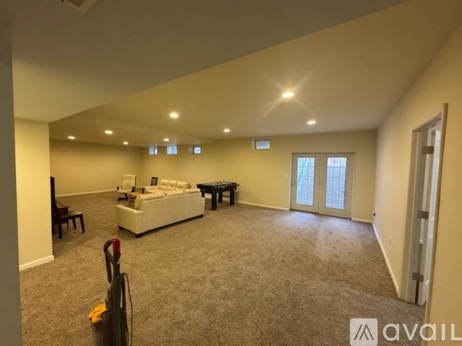 A living room with a couch, chair, and vacuum cleaner.